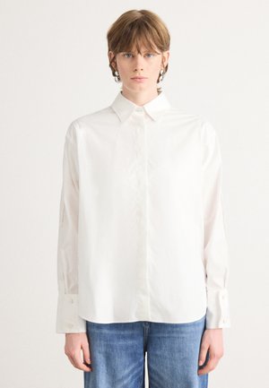 Camicia bianca in tessuto misto cotone, con maniche lunghe, colletto e polsini con bottoni. Tessuto liscio e vestibilità comoda.