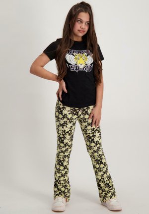 Zwart t-shirt met een gele en witte grafiekontwerp van een tijger, gecombineerd met gele bloempatronen broek op een zwarte achtergrond.
