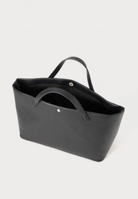 Black tote bag with soft leather material, open top, dual handles, and a snap closure. Interior is unlined and spacious.