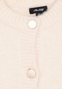 Lichte crème cardigan gemaakt van zachte, gestructureerde stof. Bevat een geribbelde kraag en een enkele zilveren knoopsluiting. Etiket zichtbaar aan de binnenkant.
