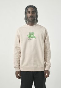 Light beige sweatshirt made of soft fabric. Features a green graphic design with text "Embrace the Timeout" on the front. This design includes playful elements.