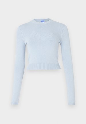 Pulover scurt de culoare albastru deschis, cu mâneci lungi. Prezintă un guler și o margine ribbată, cu un logo texturat subtil pe partea din față.