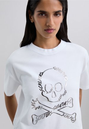 T-shirt bianca in cotone con una grafica argentata di un teschio con le ossa incrociate, con la parola "SCALPERS" integrata nel design.