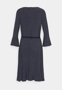 Marinblå klänning med trumpetärmar, prickmönster, bälte i midjan och utsvängd nederkant. Bakåtsidan visar en knappstängning.