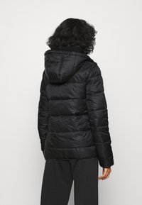 Chaqueta de abrigo negra con capucha, que presenta un diseño acolchado, textura suave y mangas largas. La parte trasera tiene un corte recto. Ligera y cálida.