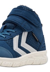 Niebieskie sneakersy typu high-top, wykonane z mieszanki materiałów siatkowych i zamszowych, z białymi chevronami, rzepem oraz teksturowaną gumową podeszwą.