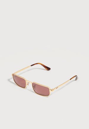 Rechthoekige zonnebril met gouden montuur, bruin getinte glazen en schildpadkleurige pootjes, plat neergelegd op een lichte achtergrond.