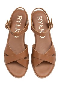Brązowe skórzane sandały z krzyżującymi się paskami, regulowanym paskiem na kostkę i wyściełanym wkładką. Gładka faktura, płaska podeszwa i logo marki.