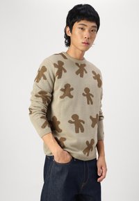 Knit sweater in beige with brown gingerbread man patterns, crew neck, and long sleeves; features ribbed cuffs and hem.