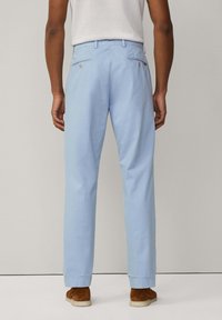 Pantaloni di cotone azzurri chiari con vestibilità dritta, tasche visibili con bottoni e orlo a pantalone. La vista posteriore mostra una texture liscia e un design su misura.