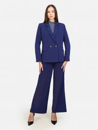 Granatowa marynarka o dopasowanym kroju z podwójnymi złotymi guzikami, w połączeniu z szerokimi granatowymi spodniami i wzorzystą bluzką w granatowo-białe desenie.
