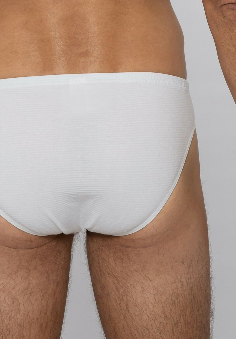 Culottes en coton blanc avec une texture côtelée. Le design présente une taille basse et une ceinture élastique minimaliste, mettant l'accent sur le confort et l'ajustement.