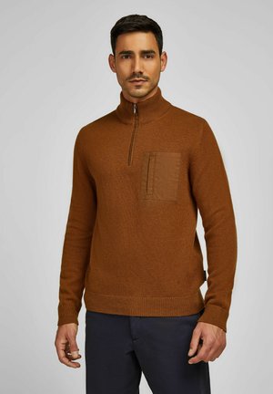 Pull en maille marron avec un col zippé à moitié, doté d'une poche à patch texturée sur la poitrine gauche et de finitions côtelées aux poignets et à l'ourlet.