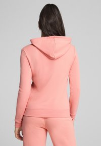 Sudadera rosa con capucha ajustable, mangas largas y corte entallado. Material suave con una textura lisa y dobladillo acanalado.