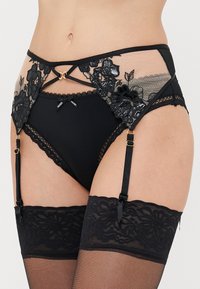 Black lace and mesh garter belt with floral embroidery, scalloped edges, gold hardware accents, and accompanying black stockings.