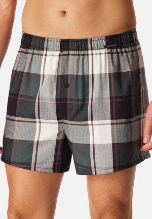 Karierte Boxershorts mit einem Muster in Schwarz, Weiß, Grau und Dunkelgrün, einem elastischen Bund und einem einzelnen vorderen Knopf zum Verschließen.