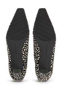 Par de zapatos de punta afilada en blanco y negro con manchas, suelas de goma texturizadas y la marca Tommy Hilfiger en los arcos.