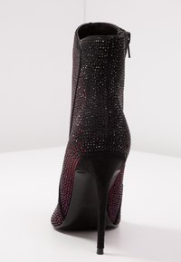 Stivaletto nero con tacco alto in suede testurizzato, decorato con strass luccicanti, dotato di zip laterale e tacco a stiletto affusolato.