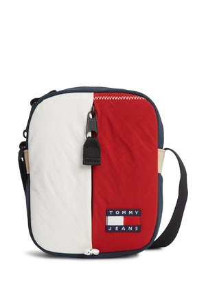 Kompakt crossbody taske med lodrette hvide og røde paneler, sort lynlås med trækflig, og Tommy Jeans logo patch foran.