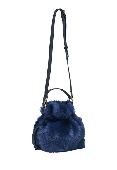 Sac à main en fausse fourrure bleu marine avec bandoulière en cuir réglable et petite poignée, texture douce et moelleuse, base ronde.