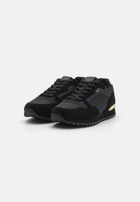Svarte joggesko laget av semsket skinn og nylon, med en teksturert overdel, polstret såle og gullakenter på hælen.