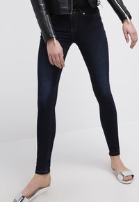 Mörkblå tajta jeans i denim med en slät yta, med midjeyta och klassisk femfickdesign.