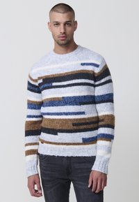 Gebreide trui met horizontale strepen in blauw, bruin en zwart op een lichte achtergrond, met een ronde hals en ribgebreide mouwen.
