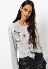 Lichtgrijze gebreide cardigan met bloemen-applicaties van pailletten, ronde halslijn, knopen aan de voorkant en een knoopstrik in de taille.