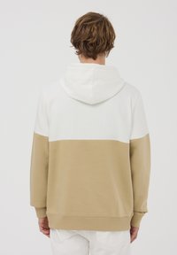 Felpa con cappuccio caratterizzata da un design color-block con sezione superiore bianca e sezione inferiore beige. Tessuto morbido, vestibilità comoda e polsini a costine.