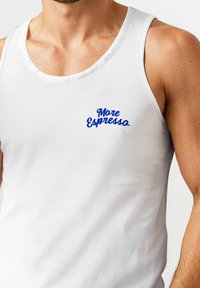 White tank top featuring a blue "More Espresso" graphic on the chest. Made of soft fabric with a scoop neckline and simple design.