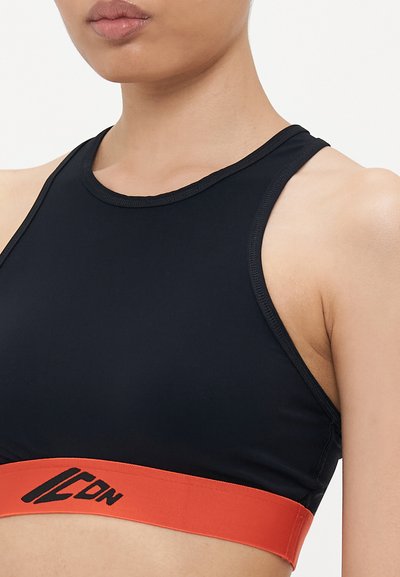 Zwarte sportbeha met een gladde textuur, voorzien van een contrasterende oranje band aan de onderkant met zwarte logo-details en een racerback-ontwerp.