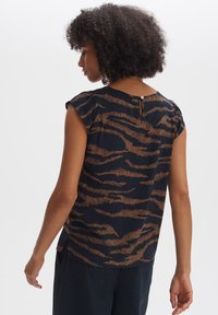 Marineblaue Bluse mit braunen Tigerstreifen, kurzen Ärmeln und einem Rückenschlitz mit Knopf. Glatte Textur, leichtes Material.