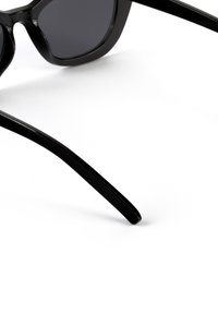 Ochelari de soare negri cu un cadru elegant și lucios, lentile întunecate și brațe curbate, fără modele vizibile sau detalii de hardware.