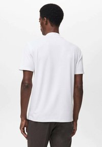 Camiseta blanca de manga corta con una textura suave y escote redondo, mostrada desde atrás. Presenta aberturas laterales en el dobladillo.