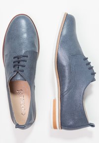 Scarpe in pelle blu forata con punta arrotondata, dettagli marroni e suola bianca. Presentano cinque fori per i lacci e una fodera interna liscia.