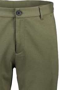 Pantaloni verde oliva realizzati in tessuto testurizzato. Presentano una parte anteriore piatta, chiusura con bottone e una tasca laterale a sinistra.