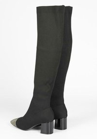 Botas de tela negras hasta la rodilla con una textura sólida, que presentan una puntera puntiaguda plateada en contraste y un tacón ancho negro.