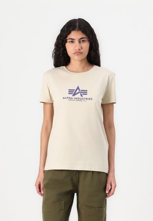 Beige cotton t-shirt with short sleeves, featuring a purple graphic logo "ALPHA INDUSTRIES" and a triangular design on the front.