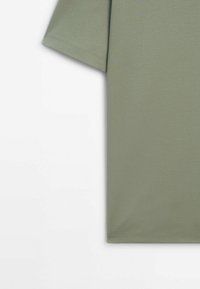 T-shirt en coton vert olive à manches courtes, col rond et texture lisse et uniforme. Aucun motif ou accent visible.
