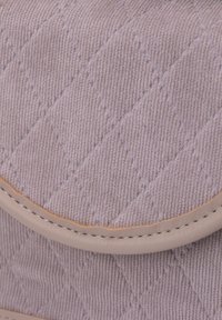 Lavet quiltet lavendelfarvet stof med diamantmønster, prydet med en glat beige læderkanter og kontrasterende syninger.