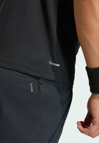 Čierne športové tričko s logom "CLIMACOOL" na leme, v kombinácii s čiernymi textúrovanými šortkami so podobným logom na vrecku.