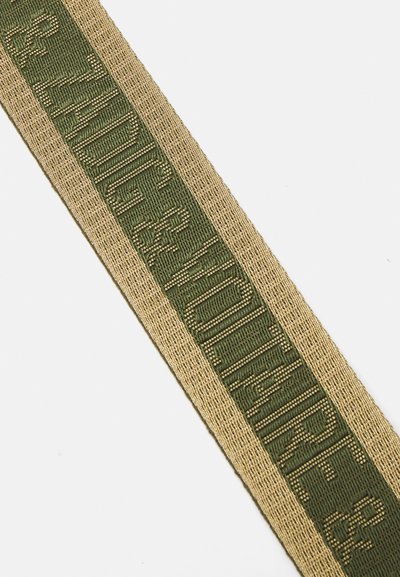 Ruban tissé vert avec des accents dorés, arborant un texte en relief "Zadig & Voltaire." Texture lisse avec un motif.