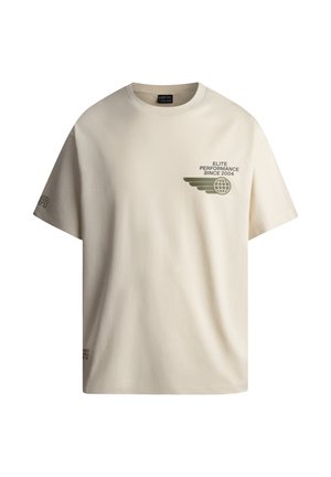 Beżowa bawełniana t-shirt w luźnym kroju, z zielonym nadrukiem na klatce piersiowej i haftowanym logo na lewym rękawie.