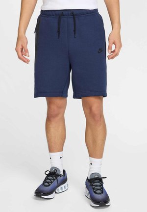 Pantaloni corti da sudore blu navy con vita elasticizzata, cordino regolabile, tasche laterali e logo Nike nero sulla gamba sinistra.