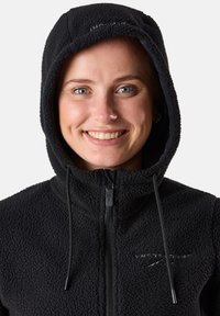 Schwarze Fleecejacke mit Kapuze, ausgestattet mit einer strukturierten Außenseite, Reißverschluss und Kordeln am Hals. Logo auf der Brust sichtbar.