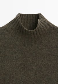 Maglione a collo alto in verde oliva scuro, lavorato a maglia, con un colletto a coste e una texture morbida. La vista ravvicinata mostra cuciture regolari e un materiale accogliente.