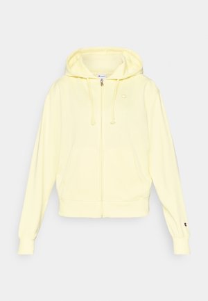 Sweat à capuche jaune zippé en tissu doux, doté d'une capuche, d'une poche kangourou et d'un logo sur la poitrine et la manche. Poignets et ourlet côtelés.