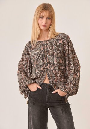 Blusa fluida de tejido oscuro con intrincados patrones florales y geométricos en tonos de melocotón y crema; abertura frontal con botones y mangas plisadas.