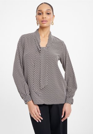 Blusa a maniche lunghe in tessuto leggero con motivo geometrico nei colori nero, beige e arancione. Vestibilità comoda con colletto a pieghe.