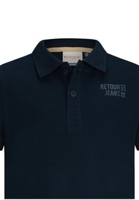 Granatowa koszulka polo o miękkiej teksturze, z dwoma guzikami i kołnierzykiem. Z przodu znajduje się branding "RETOUR JEANS EST. 89" w kontrastującym odcieniu niebieskiego.